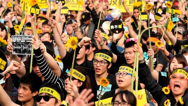Demonstrators holding sunflower shout slogans in front of the Presidential Office in Taipei on March 30, 2014. © Reuters