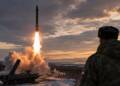 A Russian intercontinental ballistic missile launches from a snowy forested site at sunset as a soldier watches beside a mobile missile test launcher.
