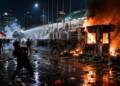 A nighttime protest riot in Jakarta, with demonstrators facing riot police amid tear gas and water cannon spray as a guard post and motorcycles burn nearby.