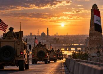 US military convoy leaving Iraq at sunset, with American flags, a war-scarred city, and the historic al-Hadba minaret draped in the Iraqi flag.
