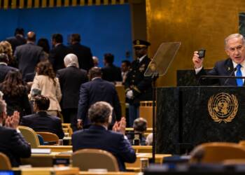Israeli Prime Minister Benjamin Netanyahu speaks at the UN General Assembly as delegates walk out of the chamber, with some remaining delegates applauding.
